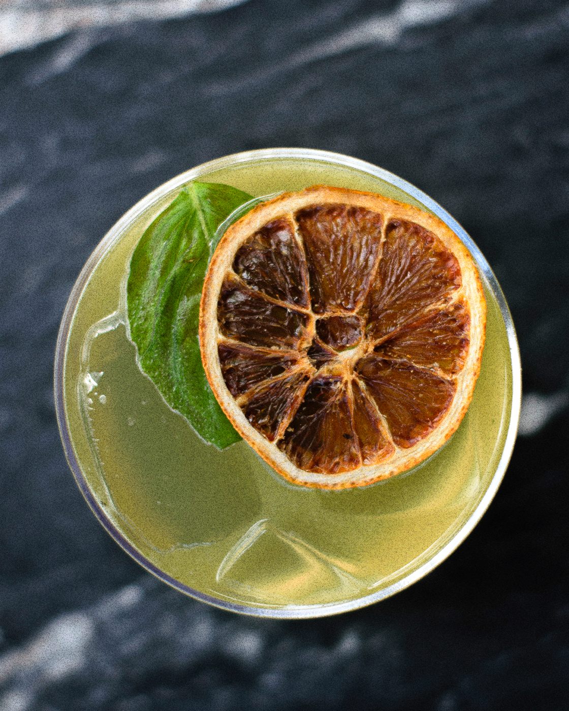 A signature cocktail with basil and dried citrus at Afterhours