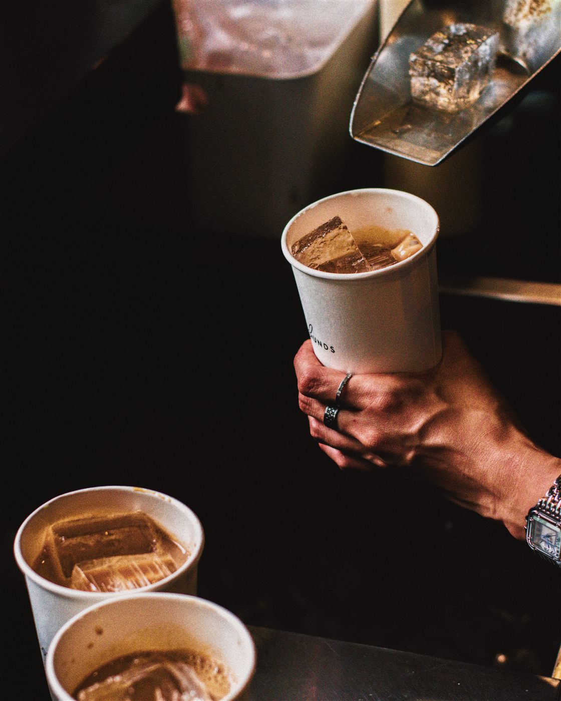 Iced coffee held by a Pilotos Grounds barista
